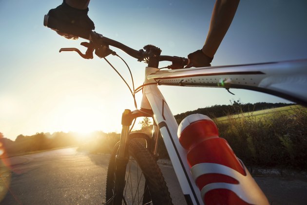 Hands in gloves holding handlebar of a bicycle