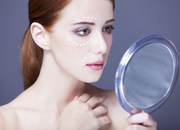 women with cosmetic cream on a chee