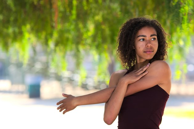 Young woman with curly hair stretching outside