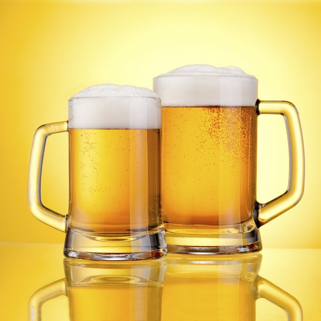 Two Mugs beer with cap of foam on yellow