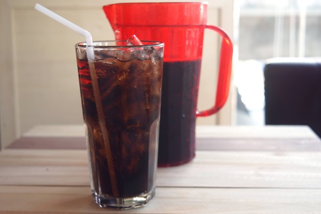glass of cola and red jar on wooden background