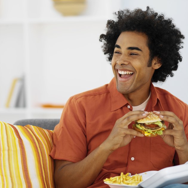 Close-up of mid adult man eating burger and French fries