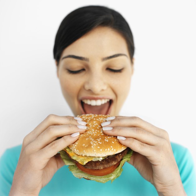 Front view portrait of young woman eating burger