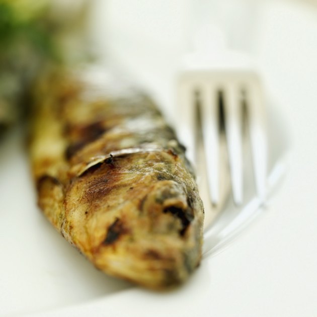 Close-up of a whole fried fish with a knife