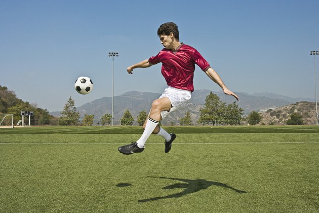 Jumping soccer player kicking ball