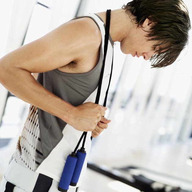 Young man standing with a skipping rope around his neck