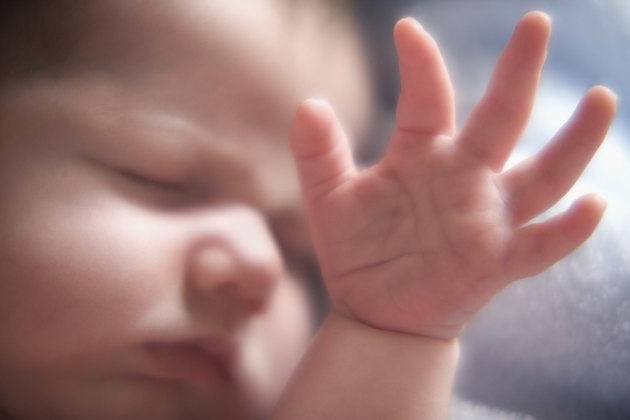 Close up of baby sleeping with hand raised