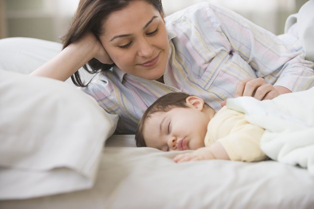 Mother laying on bed with sleeping baby