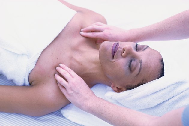 Woman getting massage, lying on back with eyes closed