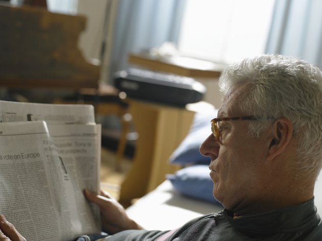 Mature man reading newspaper, close up
