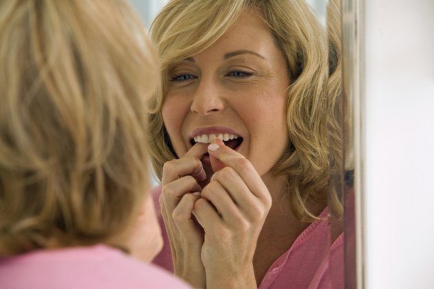 Mid adult woman flossing her teeth