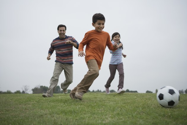 Father and children playing soccer