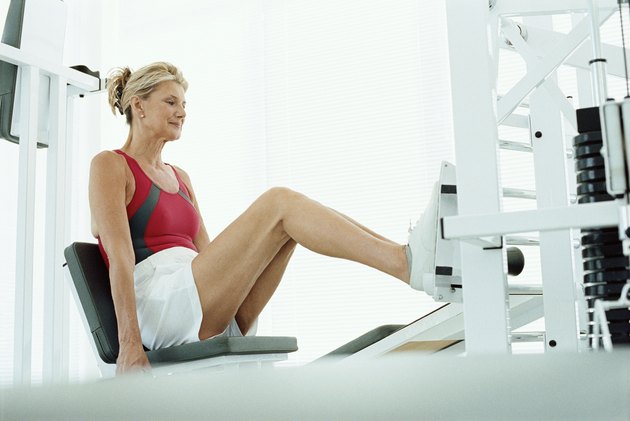 Senior woman using leg press machine in a gym