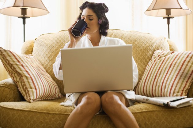 Woman in hair curlers working at home with laptop computer