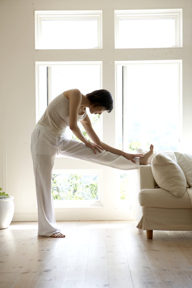 Young woman stretching legs on sofa in living room