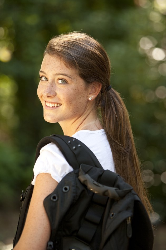 young girl with backpack looking over shoulder