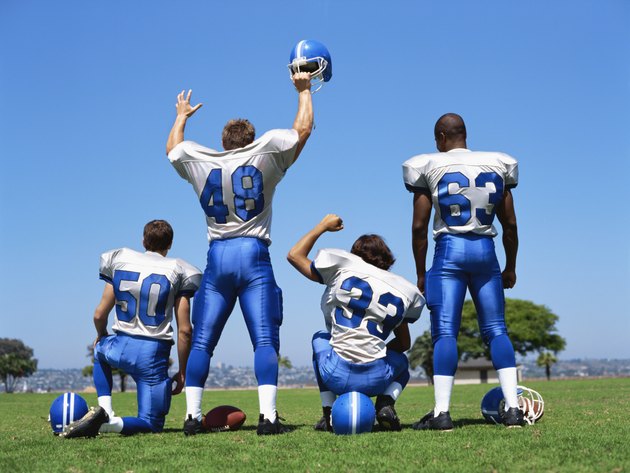 rear view of four football players on a football field
