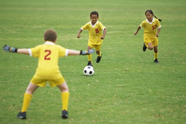 two boys and a girl playing soccer
