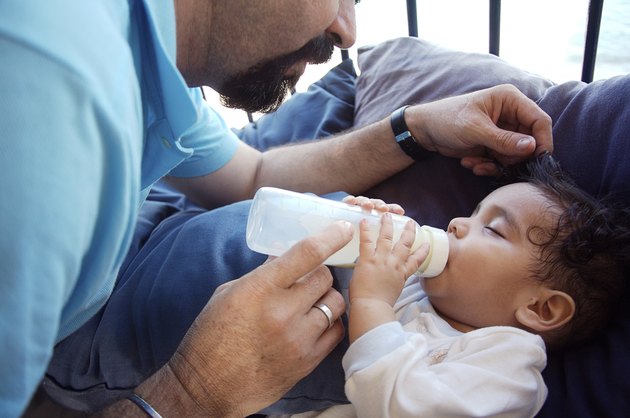 Mature man feeding his baby with a bottle