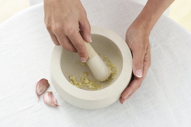 Woman crushing garlic, close up