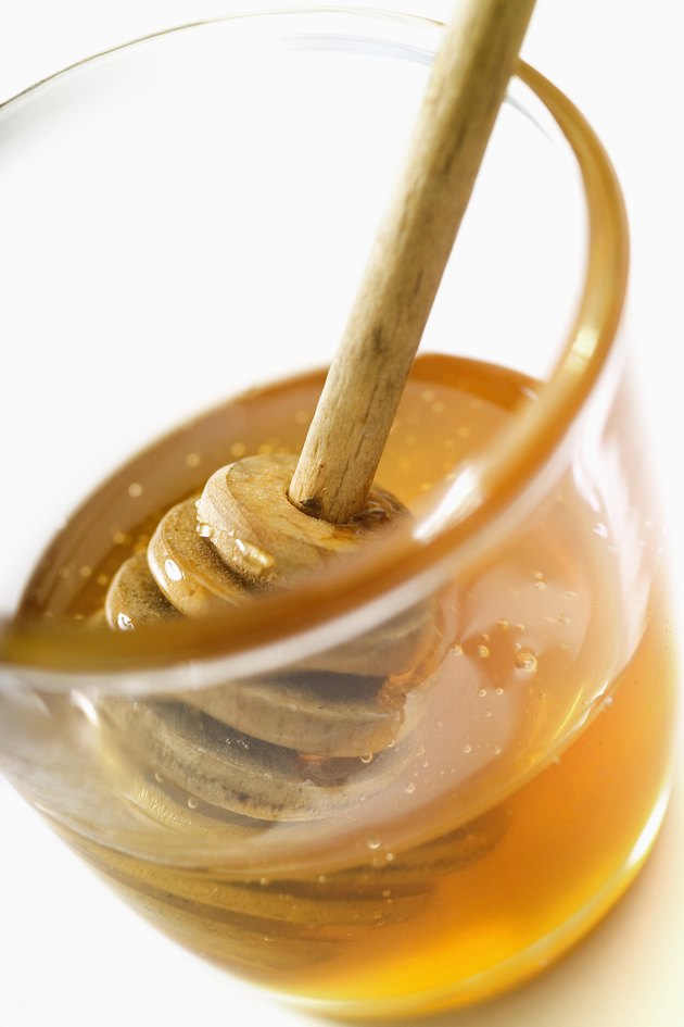 Honey dipper in jar of honey, close-up, tilt