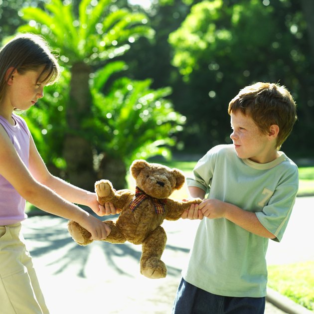boy and a girl fighting over a teddy bear