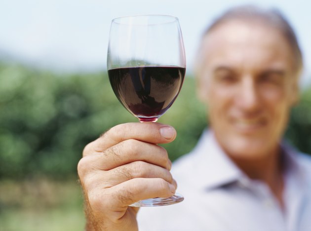 mature man showing a glass of red wine