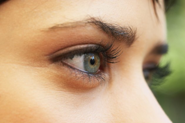 Young woman wearing eye make-up, high section, close-up