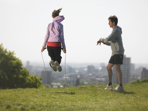 Man timing woman skipping, city in background