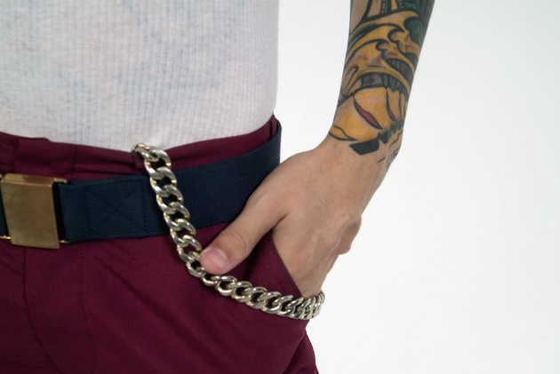Mid section image of man's hand in pocket; man has tattoo and chain on pants, close-up