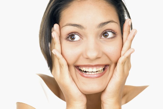 Portrait of a young woman holding her face in surprise