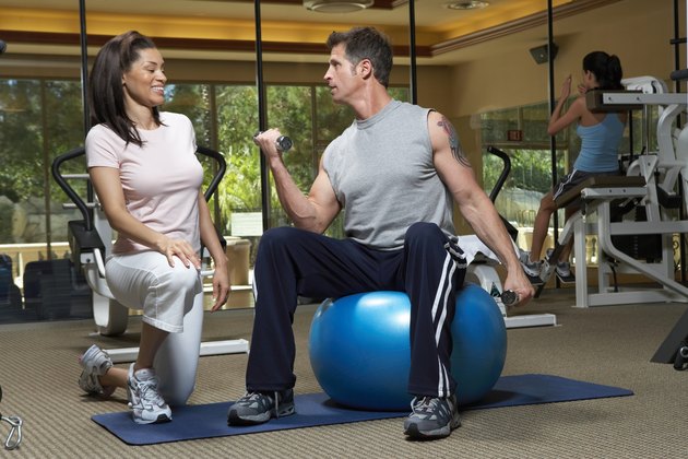 Woman instructor looking at man lifting weights
