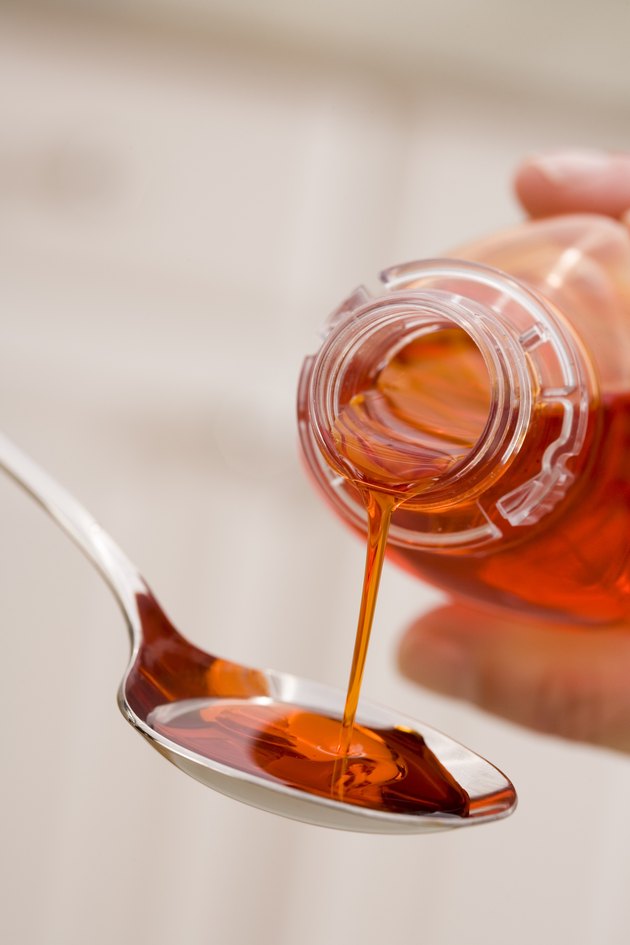 Hand pouring cough syrup into spoon