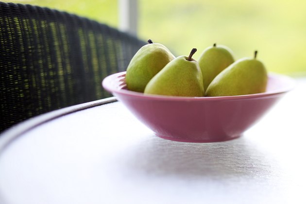 Close-up of a bowl of pears sitting on a glass table on a porch