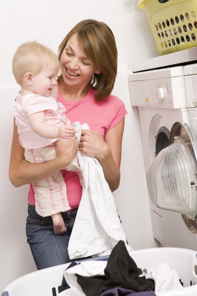 Mother holding baby and doing laundry