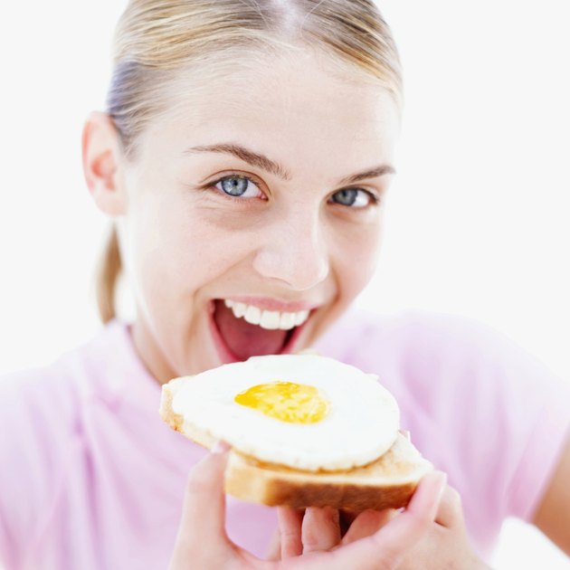 Close-up of a teenage girl (16-18) eating a fried egg on toast