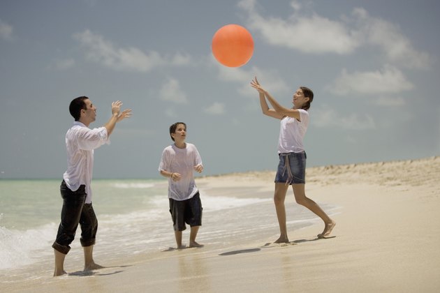 Young man with a teenage girl and a boy playing on the beach