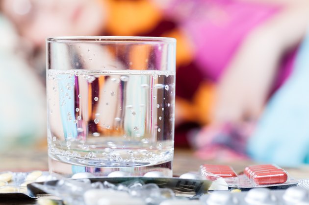 glass with water and pills on table close up