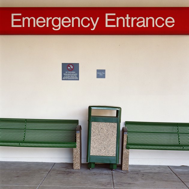 Benches and garbage can under 'Emergency Entrance' sign at hospital