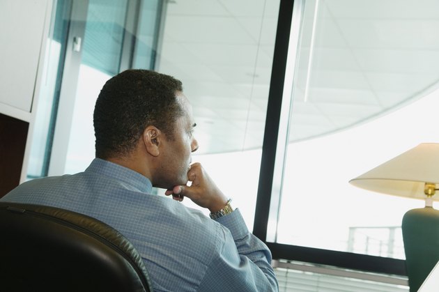 Rear view of a businessman sitting on a chair with his hand on his chin