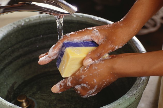 Woman washing hands with sponge in bathroom sink, close-up of hands