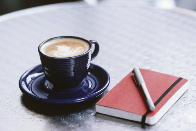 Cup of coffee, notebook and pen lying on table