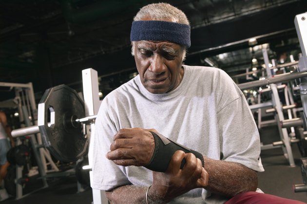Senior man applying wrist strap in gym, close-up