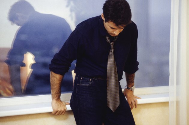 Man leaning against window sill, three quarter length