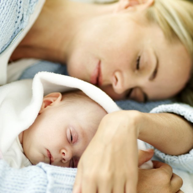 portrait of a young mother asleep holding her new born baby