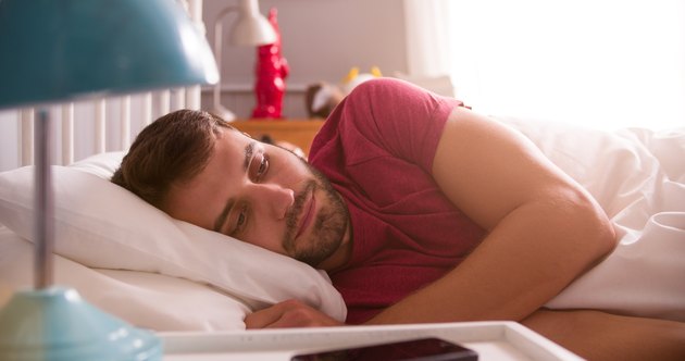 Man Lying Awake In Bed Looking Worried