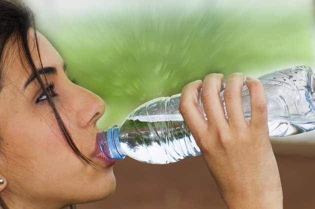 Profile of young woman drinking from a water bottle