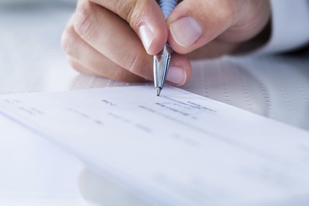 Close-up Of Hand Filling Cheque