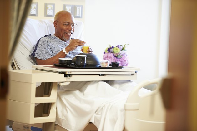 Senior Male Patient Enjoying Meal In Hospital Bed