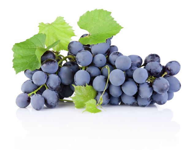 Fresh bunch of grapes with leaves isolated on white background